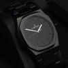 Reloj negro con 3 manecillas plateadas y dial negro con fecha