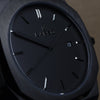 Reloj negro con 3 manecillas negras y dial negro con fecha