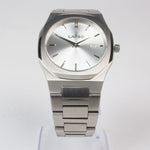 Reloj plateado con 2 manecillas y dial plateado con fecha